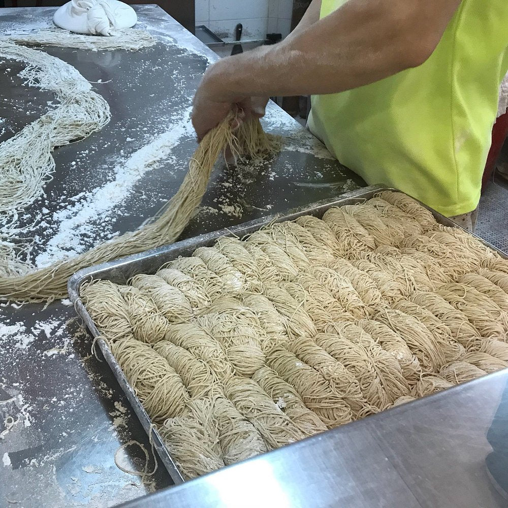 Fresh bamboo noodles being prepared